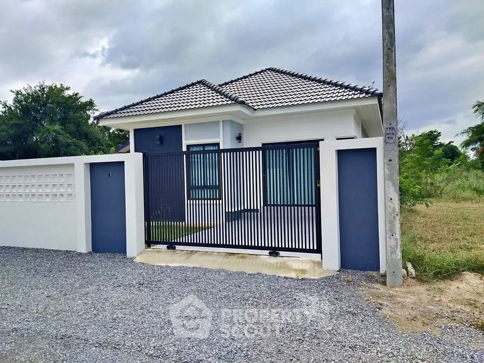 Charming modern house with sleek gate and gravel driveway, perfect for serene living.