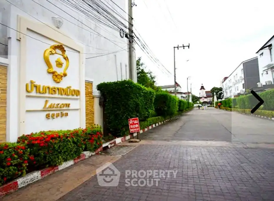 Charming residential entrance with lush greenery and welcoming signage in a serene neighborhood.