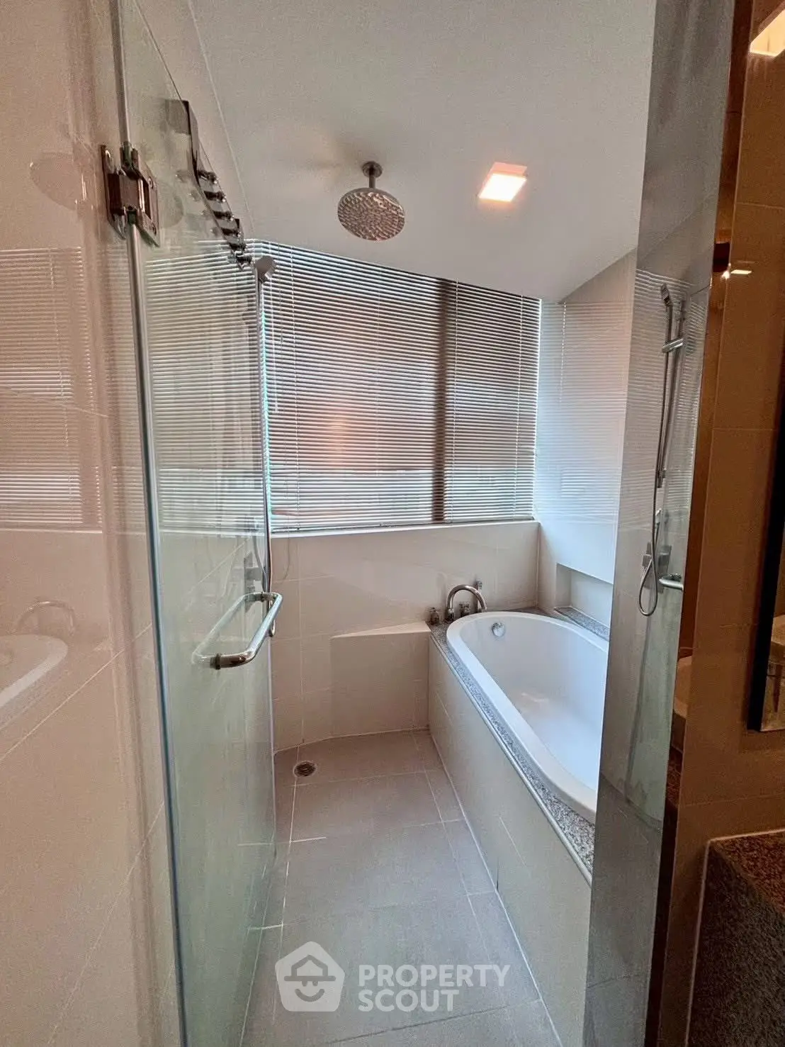 Modern bathroom with glass shower and bathtub, featuring sleek design and natural light.