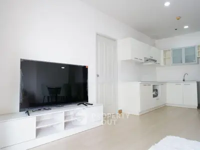 Modern open-plan living room with sleek kitchen and large TV