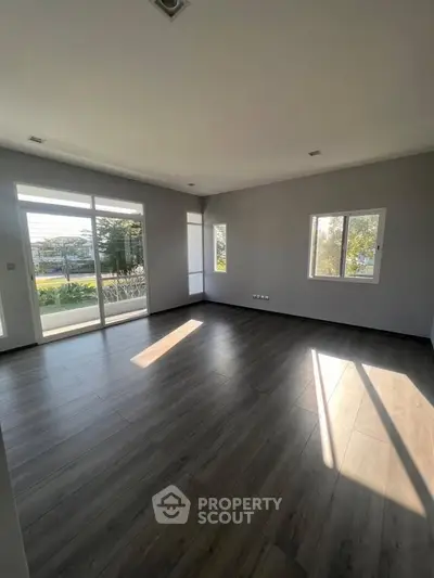 Spacious empty living room with large windows and wooden flooring