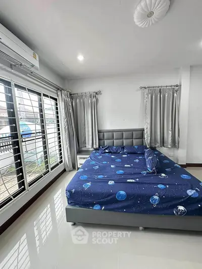 Spacious bedroom with modern decor and large windows for natural light.