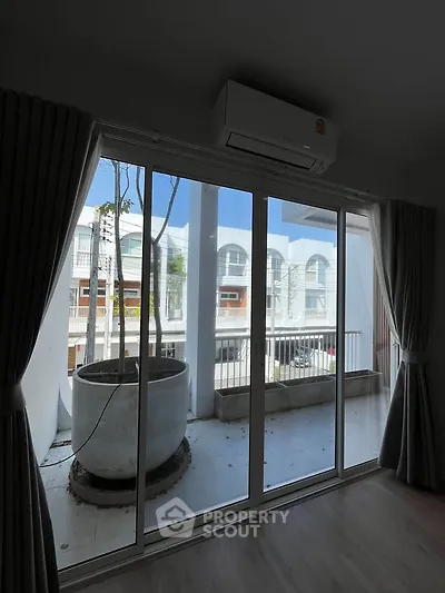Spacious balcony view with sliding glass doors and air conditioning unit.