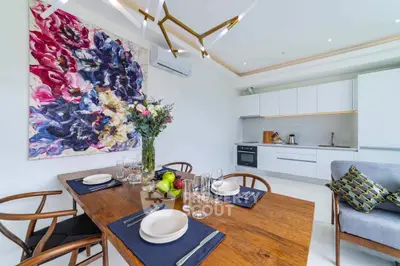 Modern kitchen with dining area, vibrant artwork, and sleek appliances in open layout.