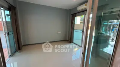 Spacious and well-lit empty room with glossy tiled flooring, large sliding glass doors leading to a balcony, and a modern air conditioning unit.