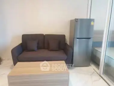Modern living room with sleek sofa and stainless steel fridge, perfect for urban living.