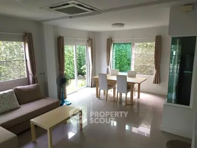 Spacious living room with modern decor and garden view, perfect for family gatherings.