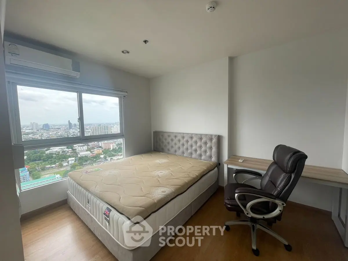 Modern bedroom with city view, featuring a comfortable bed and work desk, ideal for urban living.