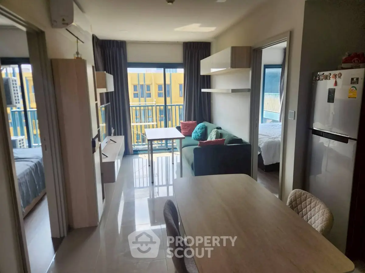 Modern apartment interior with open layout, featuring a cozy living area and balcony view.
