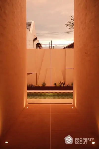 Modern architectural entrance with ambient lighting and pool view at sunset.