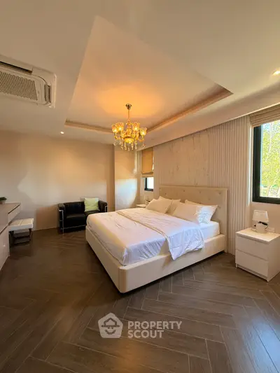 Luxurious bedroom with elegant chandelier and modern decor, featuring a spacious bed and stylish furnishings.