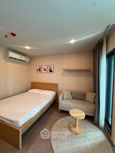 Modern bedroom with cozy seating area and stylish decor in a well-lit apartment.