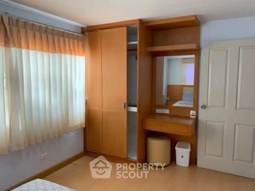 Cozy bedroom with built-in wardrobe and natural light from large window