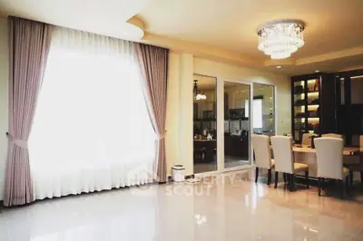 Spacious modern living room with elegant chandelier and large window, perfect for family gatherings.