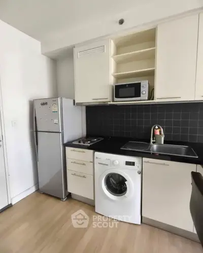 Modern kitchen with appliances including fridge, washing machine, and microwave in sleek design.