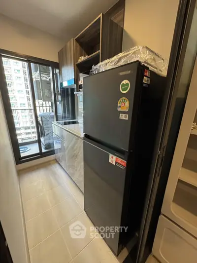 Modern kitchen with sleek black fridge and city view balcony