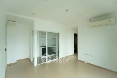 Spacious minimalist living room with air conditioning and sliding glass doors to kitchen.