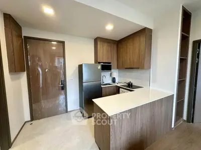 Modern kitchen with sleek wooden cabinets and stainless steel appliances in a cozy apartment.