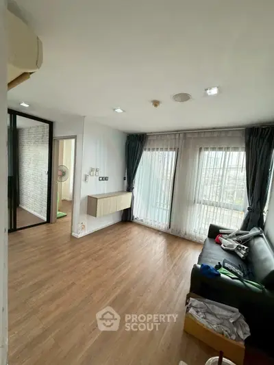 Spacious living room with wooden flooring and large windows offering natural light.