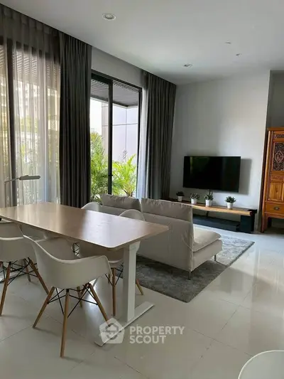 Modern living room with sleek furniture and large windows offering natural light.