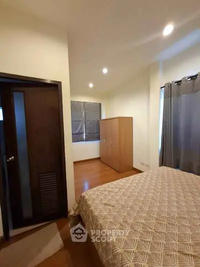 Cozy bedroom with wooden flooring and modern wardrobe in a stylish apartment.