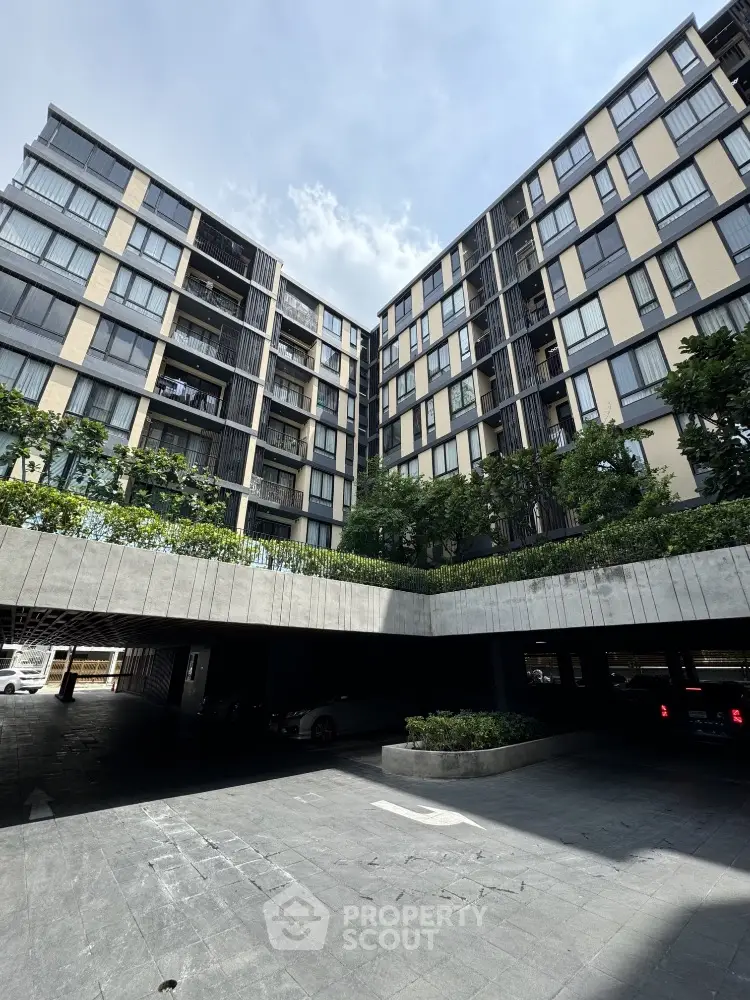 Modern urban apartment building with lush greenery and spacious parking area