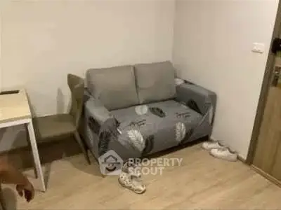 Cozy living room with a small sofa and wooden flooring, perfect for compact spaces.