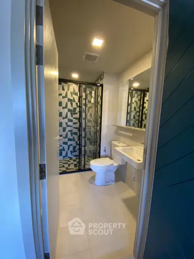 Modern bathroom with geometric tile design and glass shower enclosure