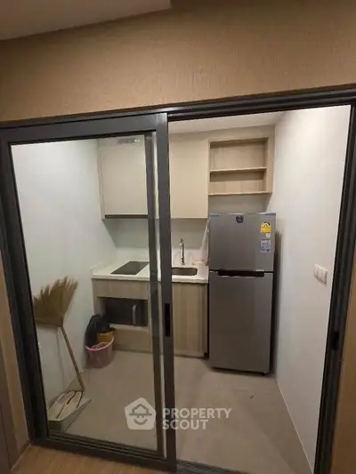 Compact modern kitchen with sleek appliances and minimalist design in a cozy apartment.