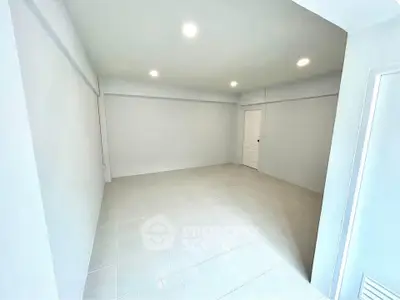 Spacious empty room with bright lighting and tiled flooring, ideal for customization.