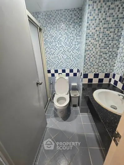 Modern bathroom with mosaic tiles and sleek fixtures in a stylish real estate property.