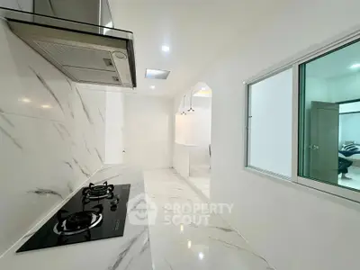 Sleek modern kitchen with marble flooring and gas stove in a bright, minimalist design.