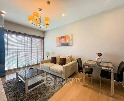 Modern living room with cozy sofa, stylish chandelier, and dining area in open layout apartment.