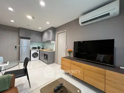 Modern living room with open kitchen, featuring sleek appliances and stylish decor.