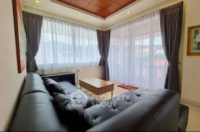 Spacious living room with large windows and modern decor, offering a bright and inviting atmosphere.