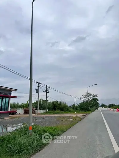 Spacious roadside property with potential for development, featuring open land and clear skies.