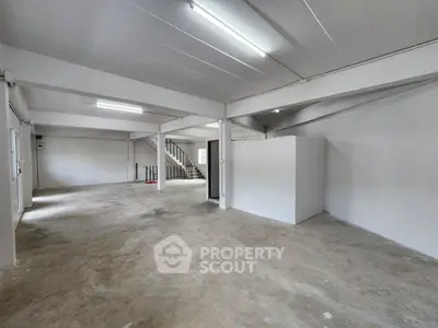 Spacious industrial-style open floor plan with concrete flooring and exposed beams, ideal for creative workspace.