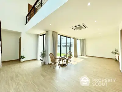 Spacious modern living room with high ceilings, large windows, and elegant wooden flooring, perfect for entertaining.