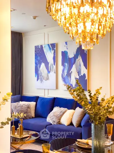 Luxurious living room with elegant chandelier and plush blue sofa, perfect for sophisticated gatherings.