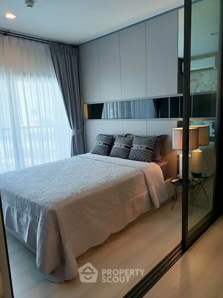 Modern bedroom with stylish decor and large window offering natural light.