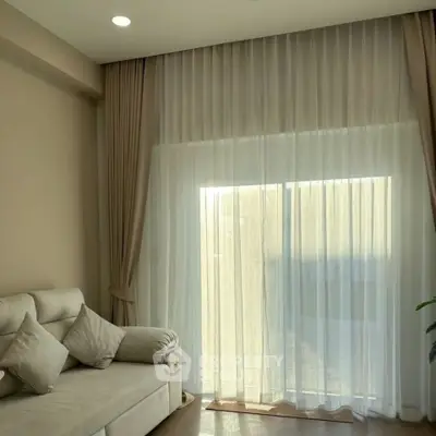 Elegant living room with soft lighting and sheer curtains, featuring a cozy sofa and neutral decor.