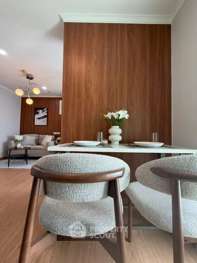 Modern dining area with stylish chairs and wooden accent wall in a cozy apartment.