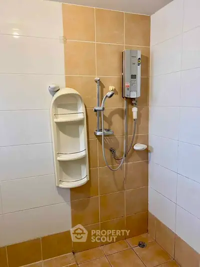 Modern bathroom with electric shower and tiled walls in a real estate property.
