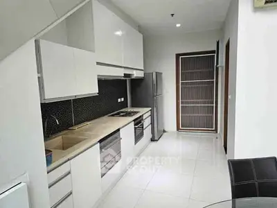 Modern kitchen with sleek white cabinets and stainless steel appliances in a contemporary home.