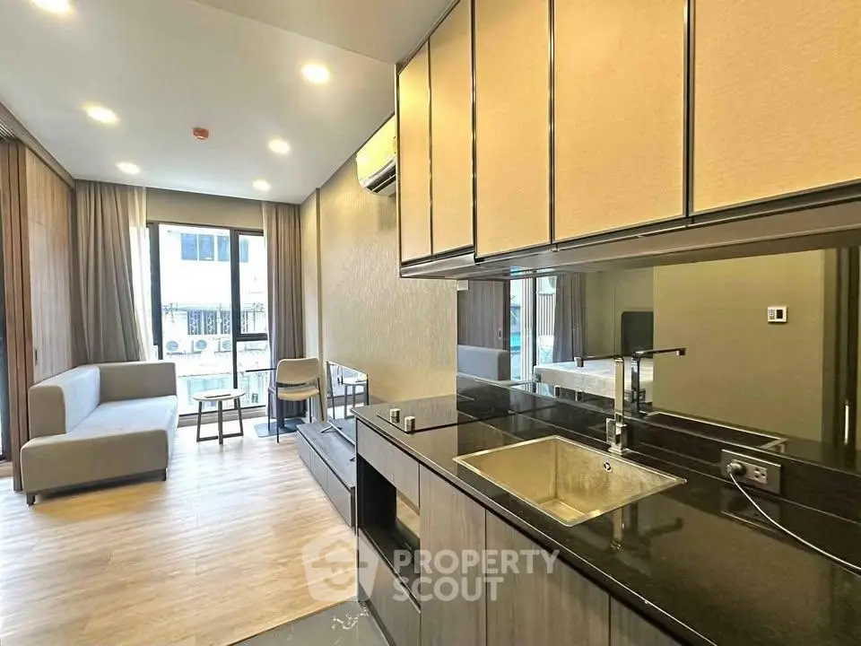 Modern open-layout living room with sleek kitchen, large windows, and stylish furnishings.