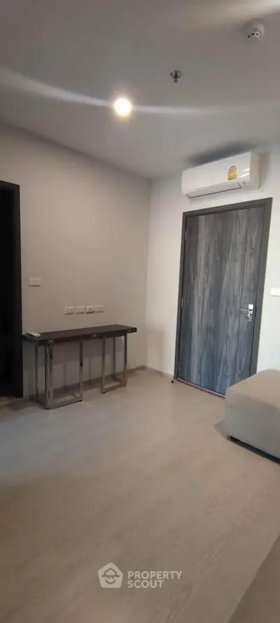 Modern minimalist living room with air conditioning and sleek wooden flooring.