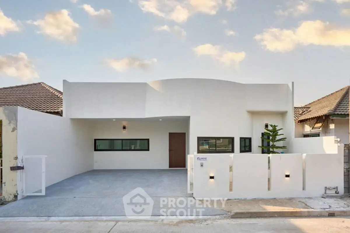 Modern minimalist white house with spacious driveway and sleek architectural design.