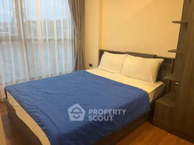 Cozy bedroom with large window and modern furnishings, perfect for relaxation and comfort.