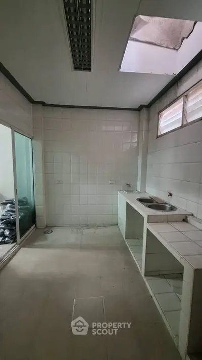 Spacious kitchen with tiled walls and natural light, ideal for culinary creativity.