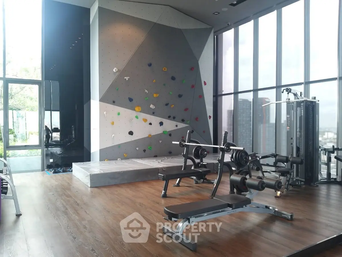Modern gym with climbing wall and city view in luxury apartment complex